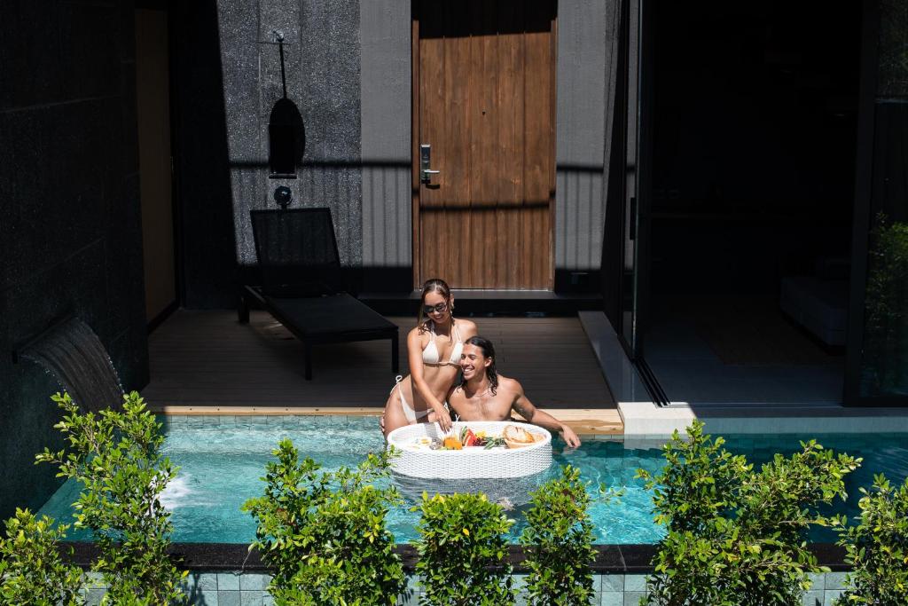 zwei Personen in einer Badewanne im Pool in der Unterkunft AKRA Collection Layan in Layan Beach