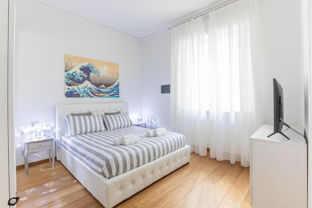 a white bedroom with a bed and a flat screen tv at Elena House Apartments in Viareggio