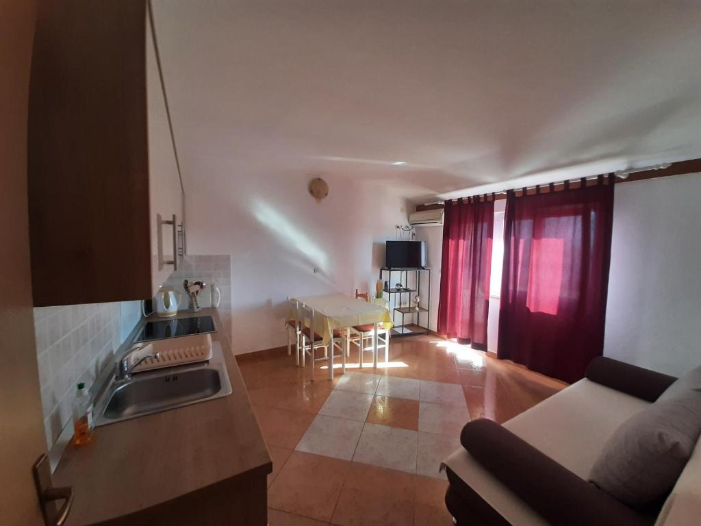 a kitchen and living room with a couch and a table at Apartments Donadic I, Caska in Novalja