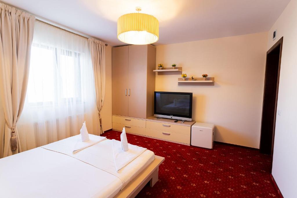 フォクシャニにあるPensiunea Oscarのベッドとテレビが備わるホテルルームです。
