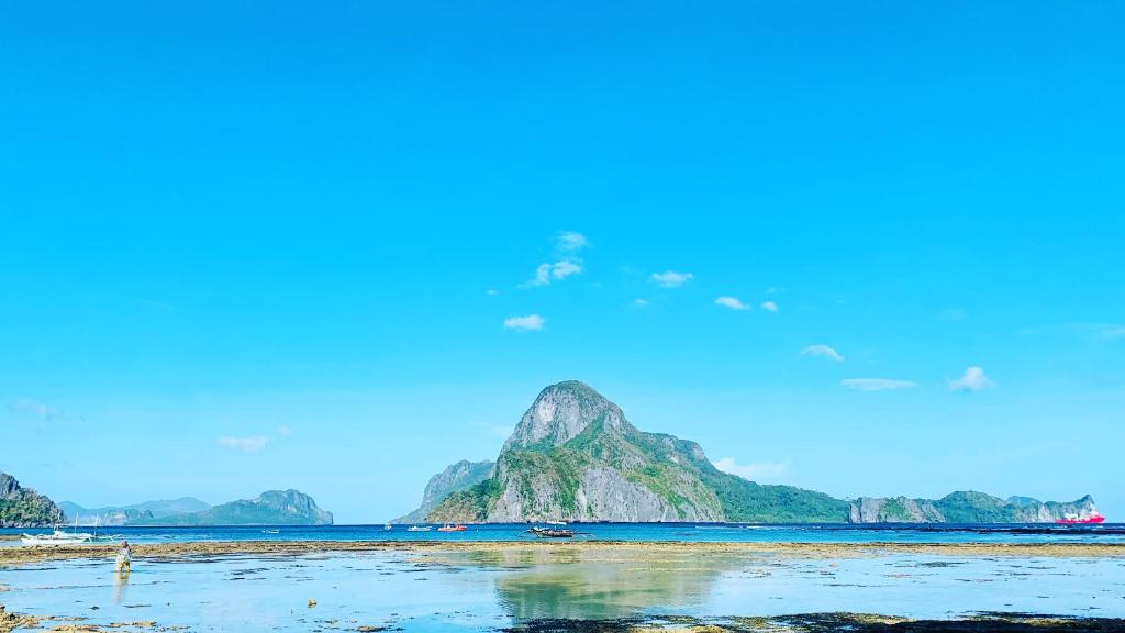 een uitzicht op een strand met een berg in het water bij Hidden of Cailan Inn in El Nido