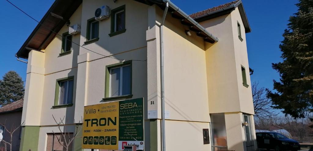 a white building with a sign in front of it at Sobe Tron Palić in Palić