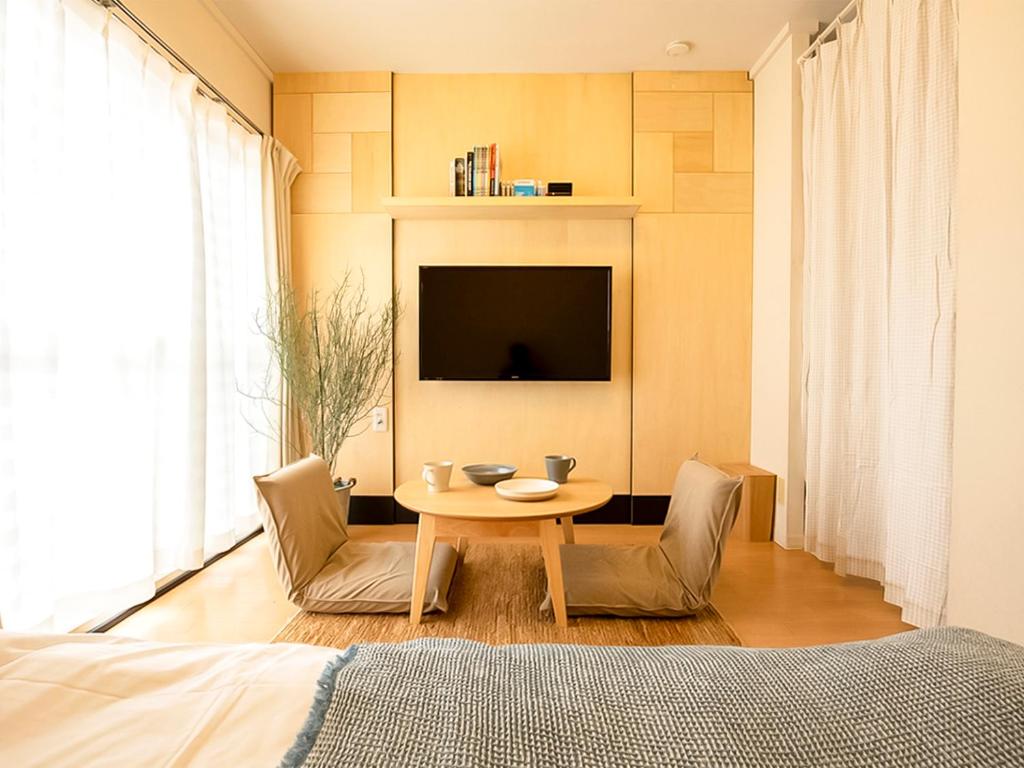 a bedroom with a table and chairs and a tv at Guesthouse Life Field in Kurashiki