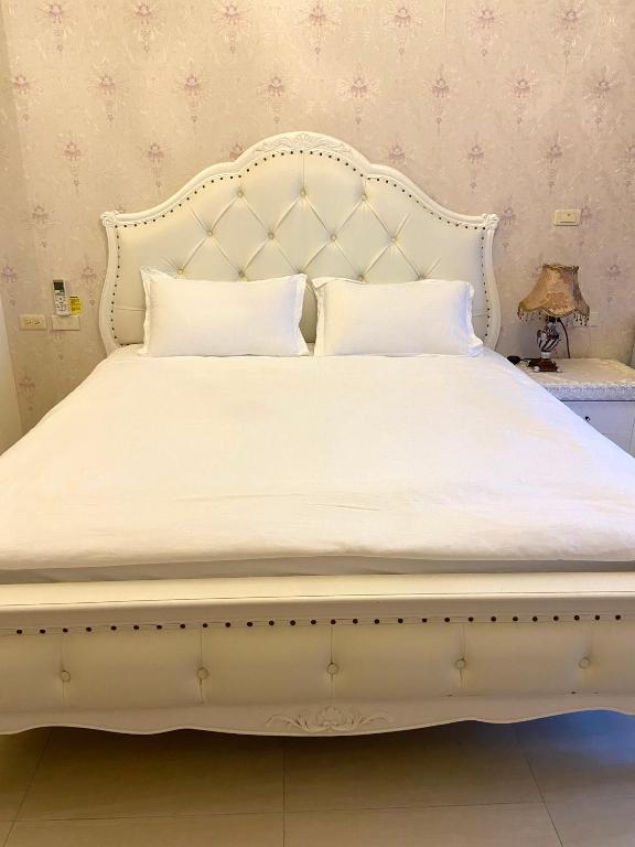 a large white bed with a white bed frame at 花蓮漫漫時光電梯包棟民宿 in Hualien City