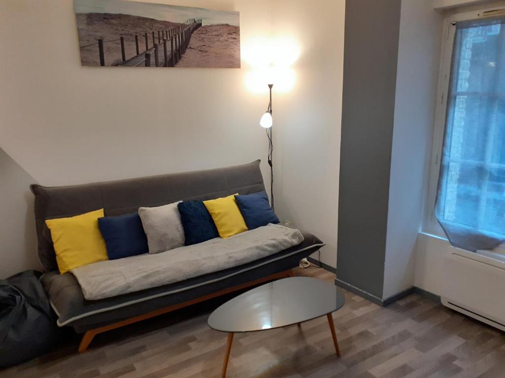 - un canapé avec des oreillers jaunes et bleus dans l'établissement Avec JARDINET sans vis à vis Plein centre ville au RDC 350m de la plage, à Dieppe