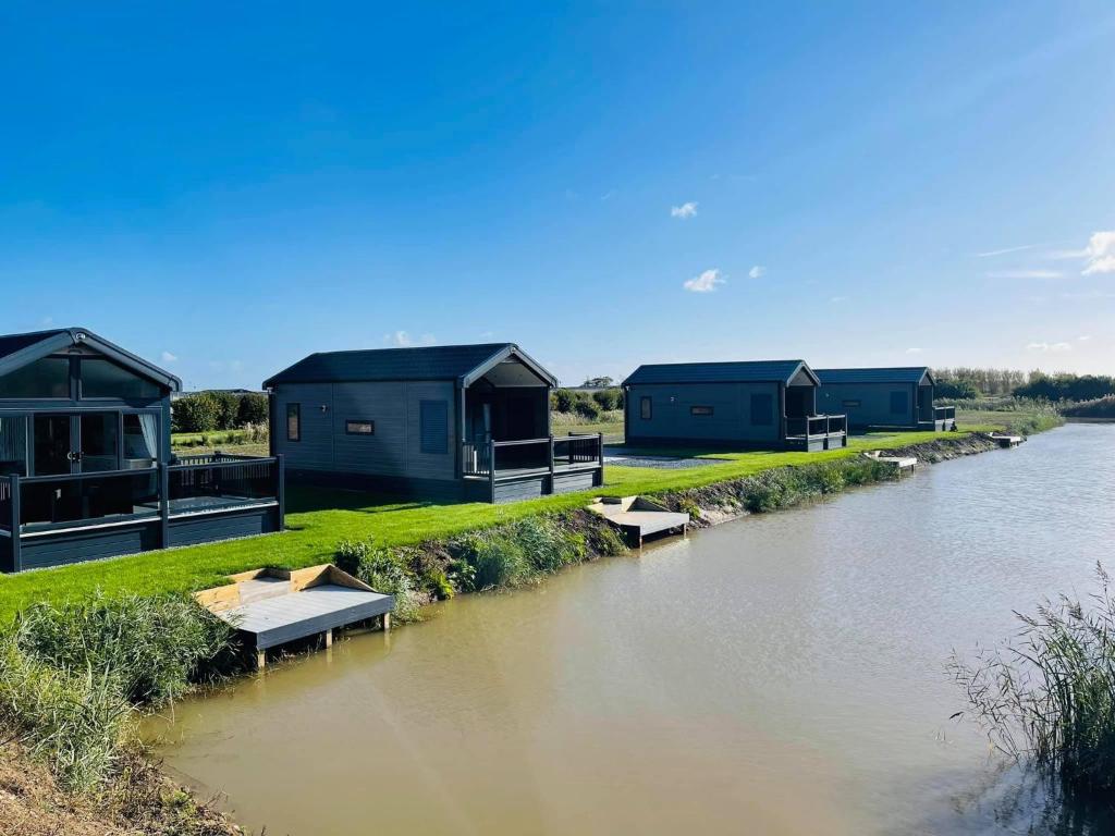 a row of houses on the side of a river at Chapel Fields Holiday Park in Chapel Saint Leonards