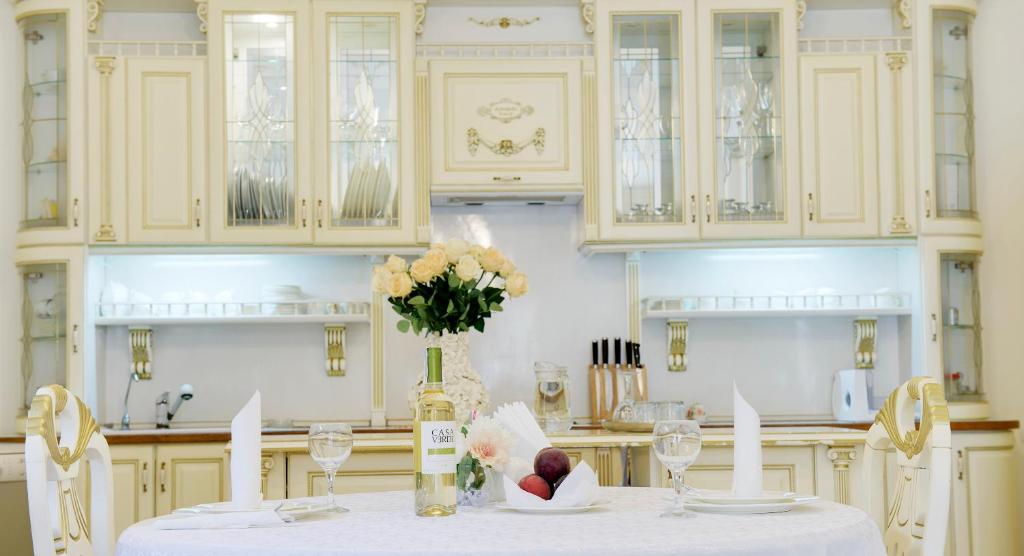 a white kitchen with a table with a vase of flowers at Pearl Mini-Hotel in Odesa