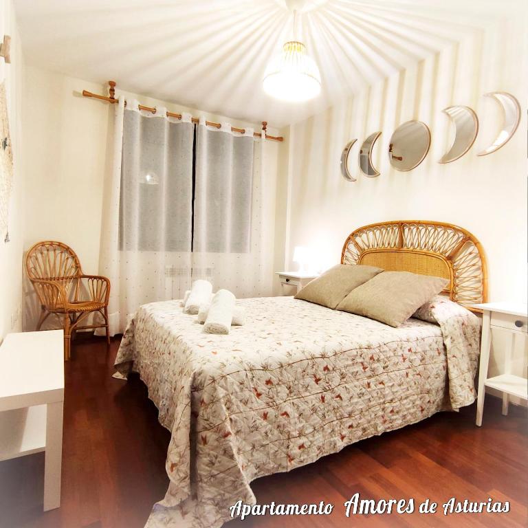 a bedroom with a bed and two chairs and a window at AMORES DE ASTURIAS in Piedras Blancas