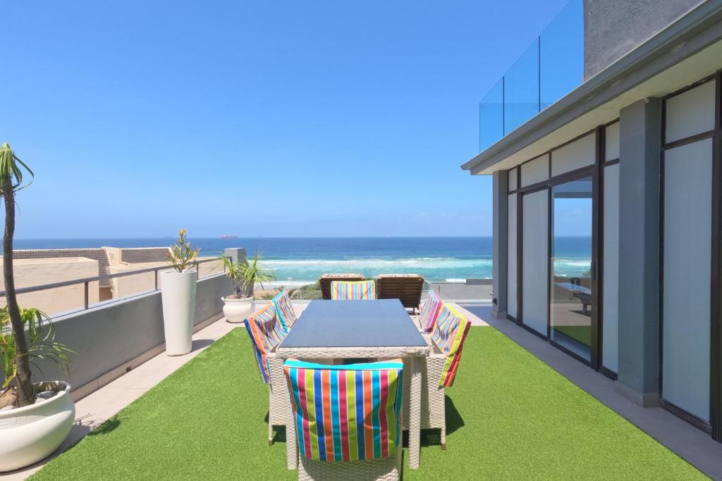 een balkon met een tafel en stoelen en de oceaan bij 41 Licorna Beach in Durban