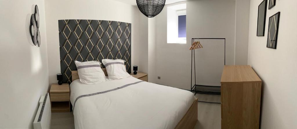 - une chambre avec un lit avec des draps blancs et une table dans l'établissement Résidence avec un T3 un T2 et un STUDIO en Centre Ville d Argeles-Gazost, à Argelès-Gazost