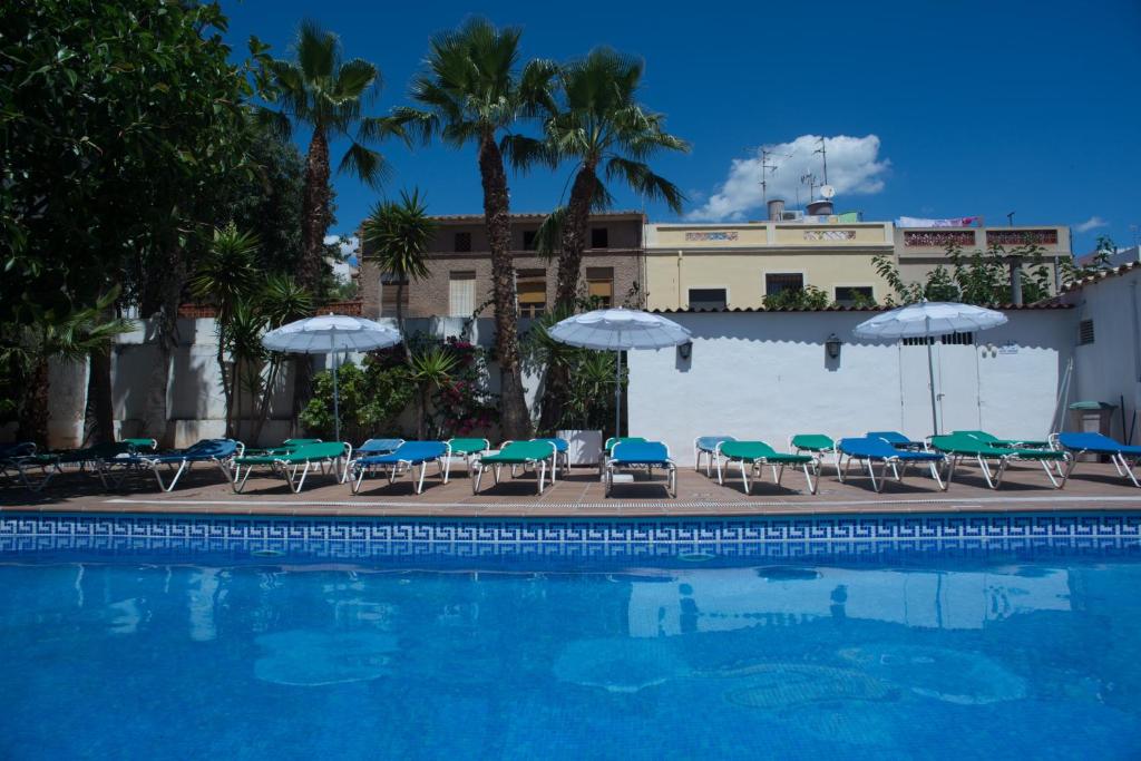 una piscina con tumbonas y sombrillas en Hotel Ecoavenida en Benicàssim