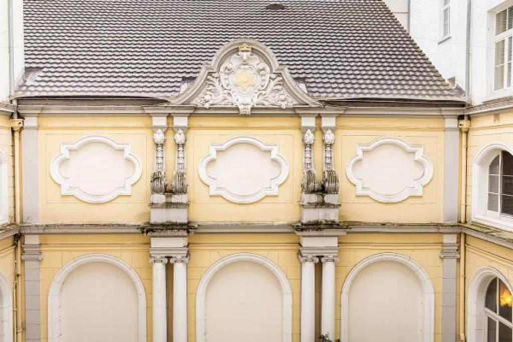 a yellow building with a clock on the side of it at ACHAT Sternhotel Bonn in Bonn