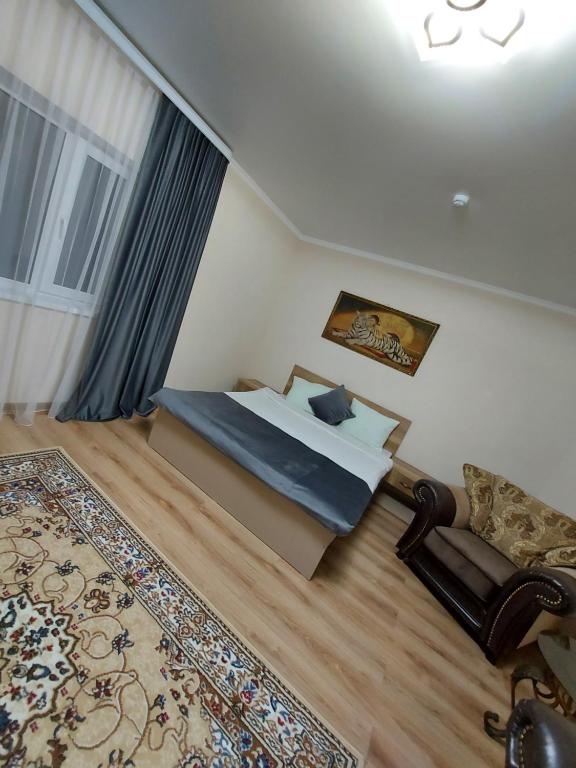 a bedroom with a bed and a chair and a rug at Hotel Дар-Ай in Kostanay