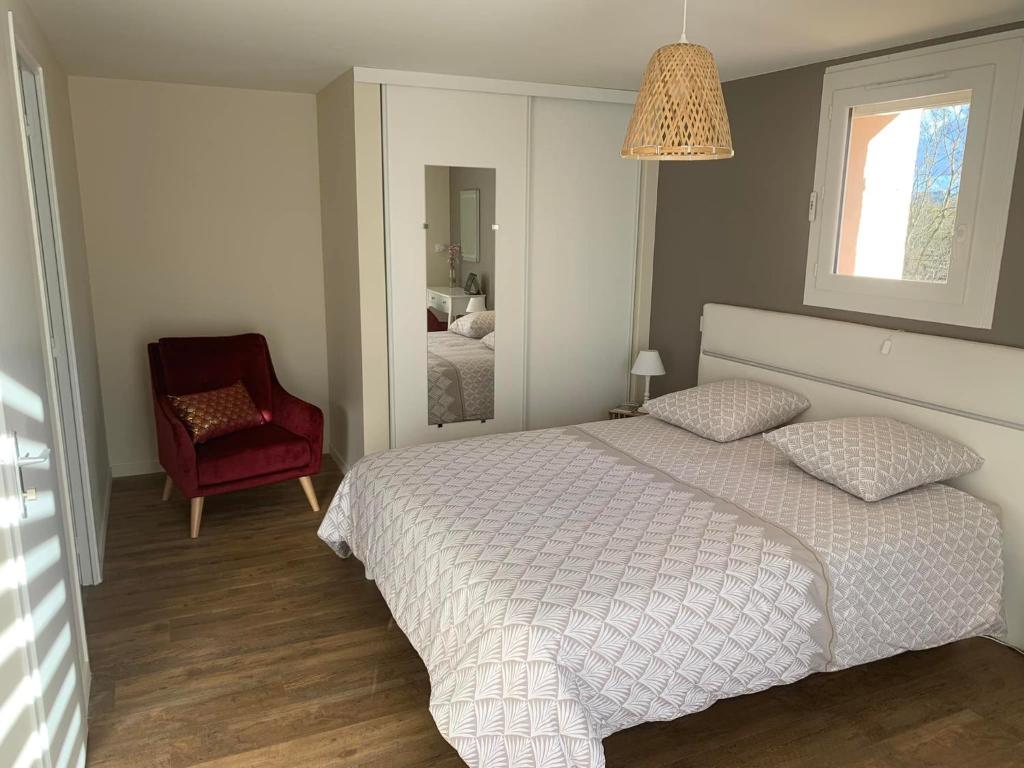 ein Schlafzimmer mit einem weißen Bett und einem roten Stuhl in der Unterkunft Domaine de Jarentin - Chambres d'hôtes in Saint-Marcel-de-Félines