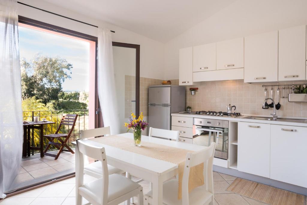 cocina blanca con mesa y sillas y balcón en Villa del Porto La Terrazza, en Portoscuso