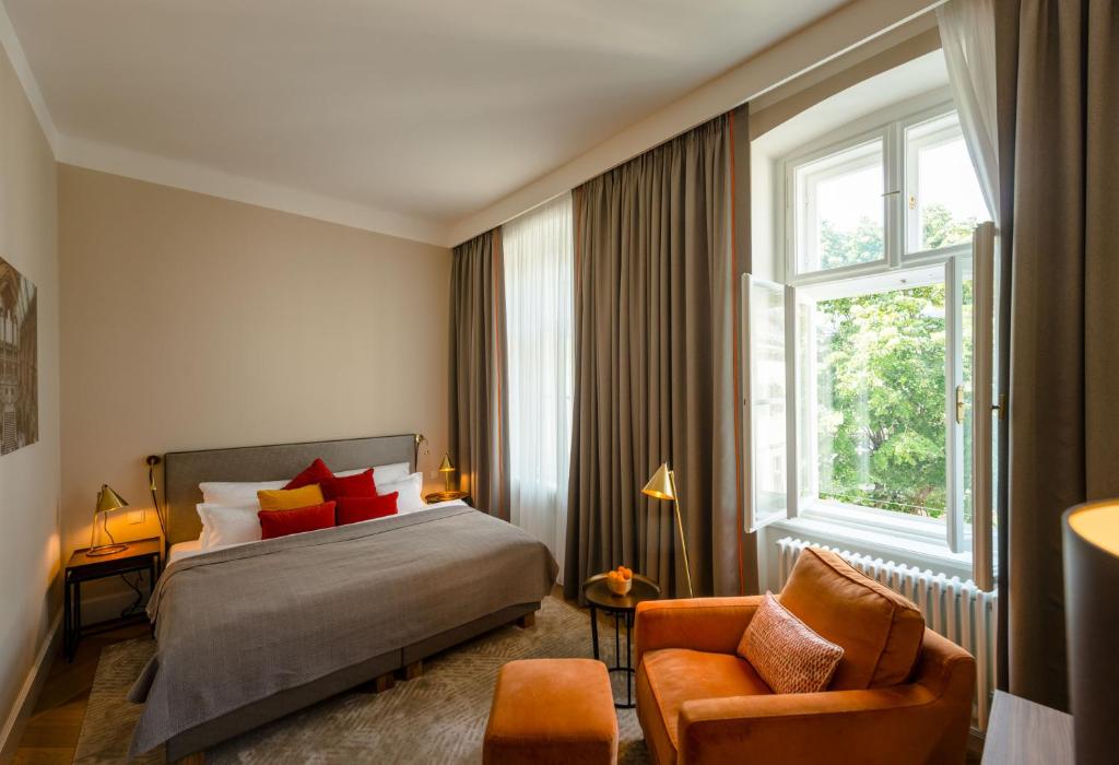 a bedroom with a bed and a chair and a window at Roosevelt Stadthaus in Vienna