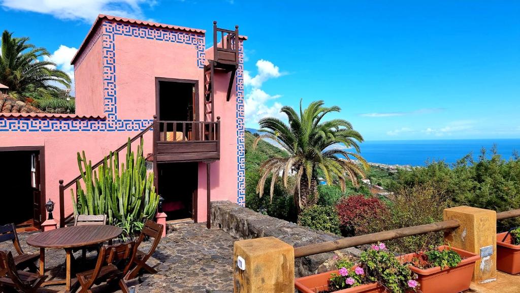 a pink house with a table and chairs and the ocean at Celeste in Mazo