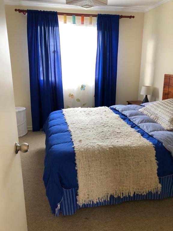 a bedroom with a bed with blue curtains and a window at Comoda y amplia casa en sector residencial in Coquimbo