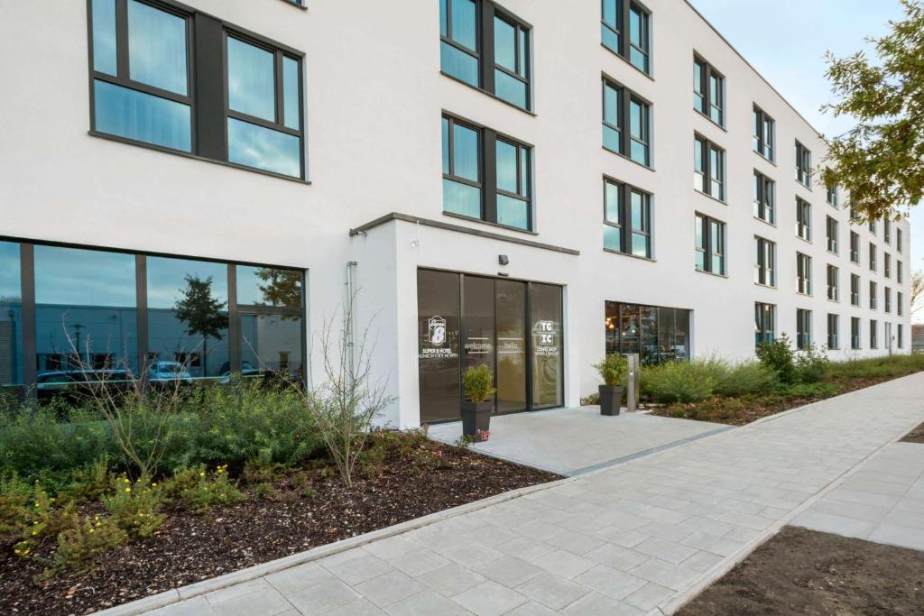 an office building with glass windows and a sidewalk at Super 8 by Wyndham Munich City North in Munich