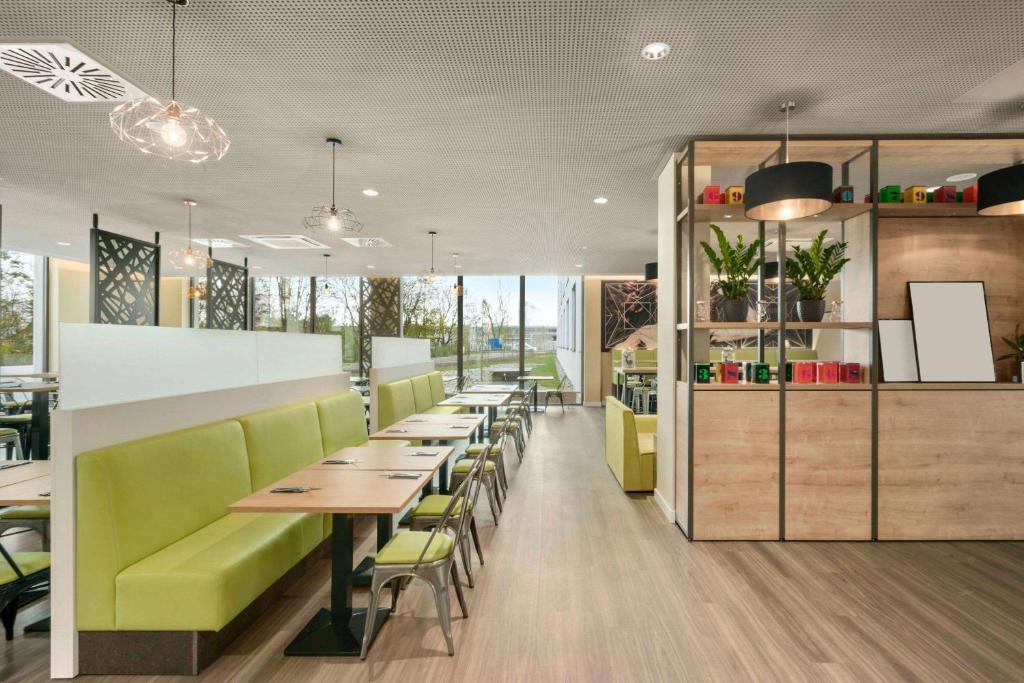 a restaurant with green chairs and tables in a cafeteria at Super 8 by Wyndham Munich City North in Munich