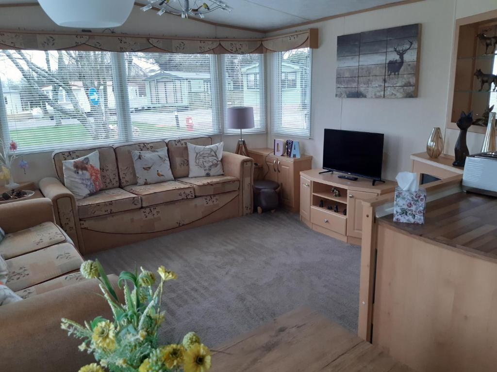 uma sala de estar com um sofá e uma televisão em 24 The Beeches Caravan Park em Gilcrux