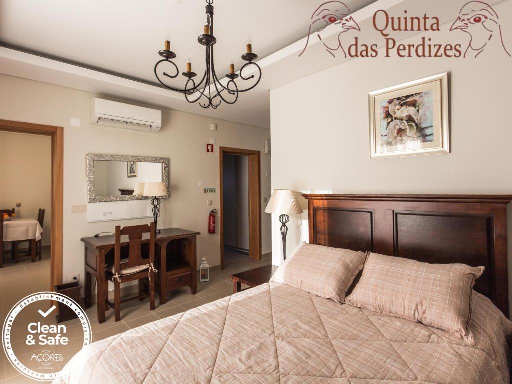 a bedroom with a large bed and a desk at Quinta das Perdizes in Ponta Delgada