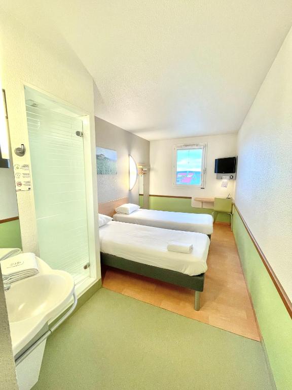 a hospital room with two beds and a sink at Hotel Ibis Budget Cosne Sur Loire in Cosne-Cours-sur-Loire