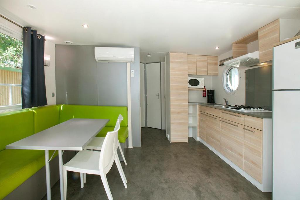 a kitchen with a table and chairs and a refrigerator at Camping la Croix du Sud in Saint-Tropez
