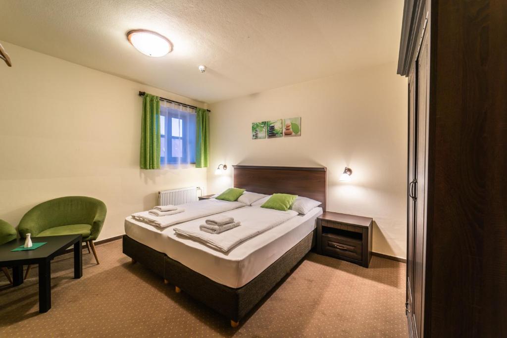 Hotel Koruna Prachatice في براكتايس: غرفة نوم بسرير وكرسي وطاولة