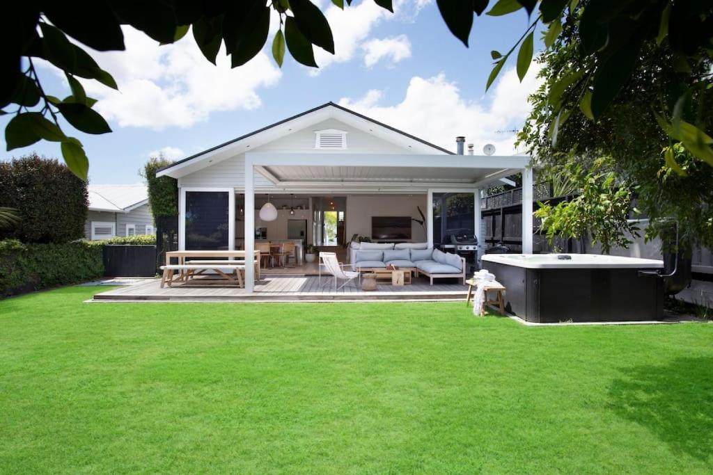 a white house with a patio and a lawn at Executive State-Of-The-Art Home - Fibre and Spa in Auckland