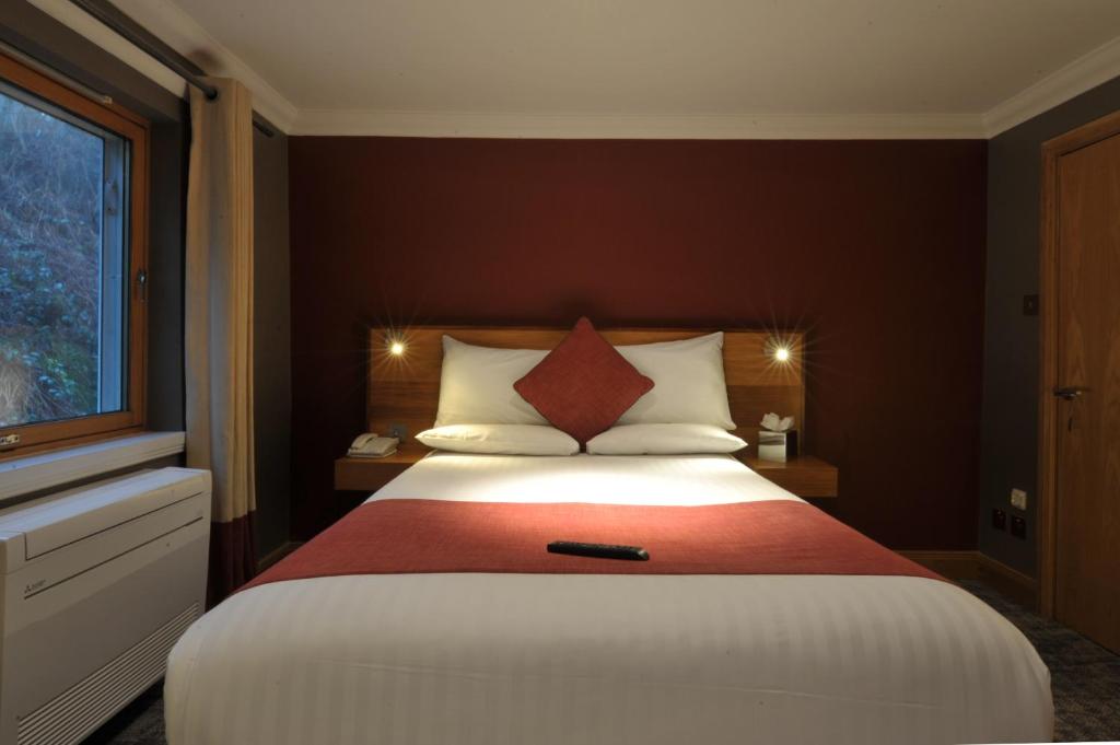 a bedroom with a bed with a remote control on it at The Inn on Loch Lomond in Luss