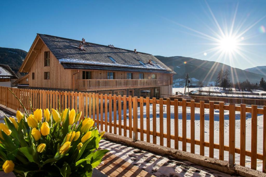 a wooden fence with yellow flowers in front of a building at Lerchpeuntgut Alpenfreud Apartments in Tamsweg