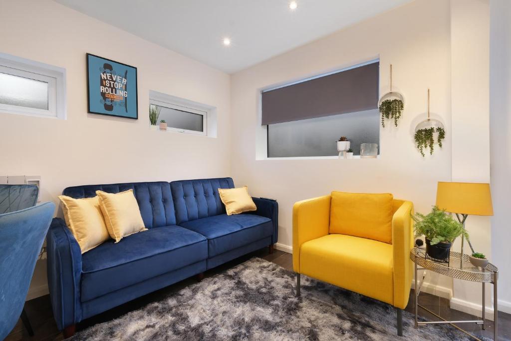 een woonkamer met een blauwe bank en 2 gele stoelen bij Kings House Apartment Hayes, West London Apt A in Northolt