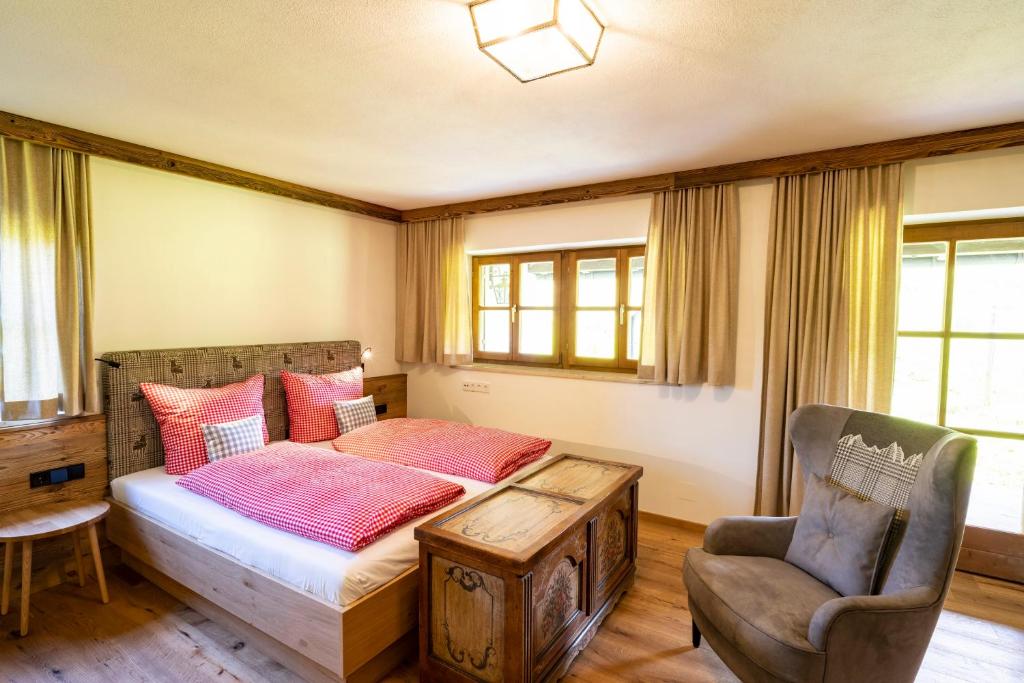 1 dormitorio con 1 cama y 1 silla en Ferienwohnung in Unterwirts Almhütte auf der Winklmoosalm en Reit im Winkl