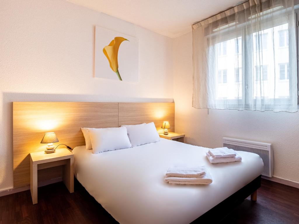 聖艾蒂安的住宿－渣油聖埃提納中央酒店，一间卧室配有一张带两盏灯的大型白色床。