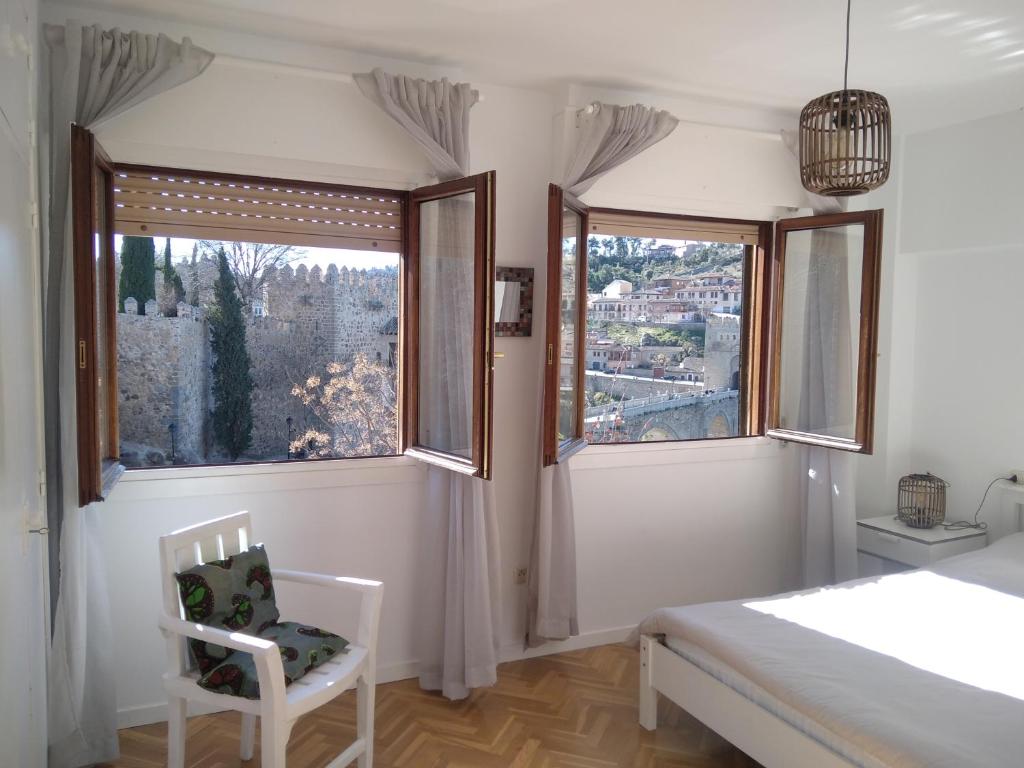 a bedroom with two windows and a bed and a chair at Casa Paseo del Tajo-CON PARKING GRATIS - 3 habitaciones in Toledo