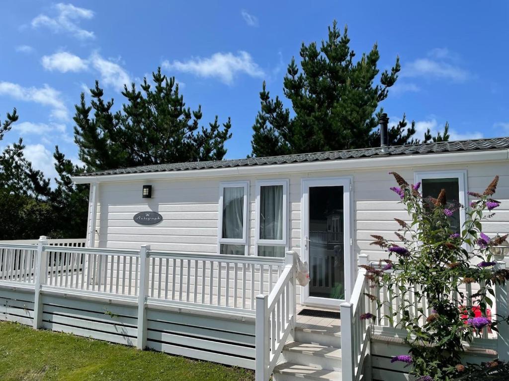 ein weißes winziges Haus mit einem weißen Zaun in der Unterkunft New Forest Retreat Shorefield Country Park in Lymington