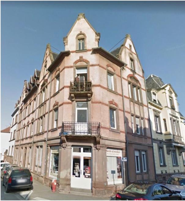 un grand bâtiment dans une rue avec des voitures garées devant dans l'établissement Le Gerwig Colmar Centre, à Colmar