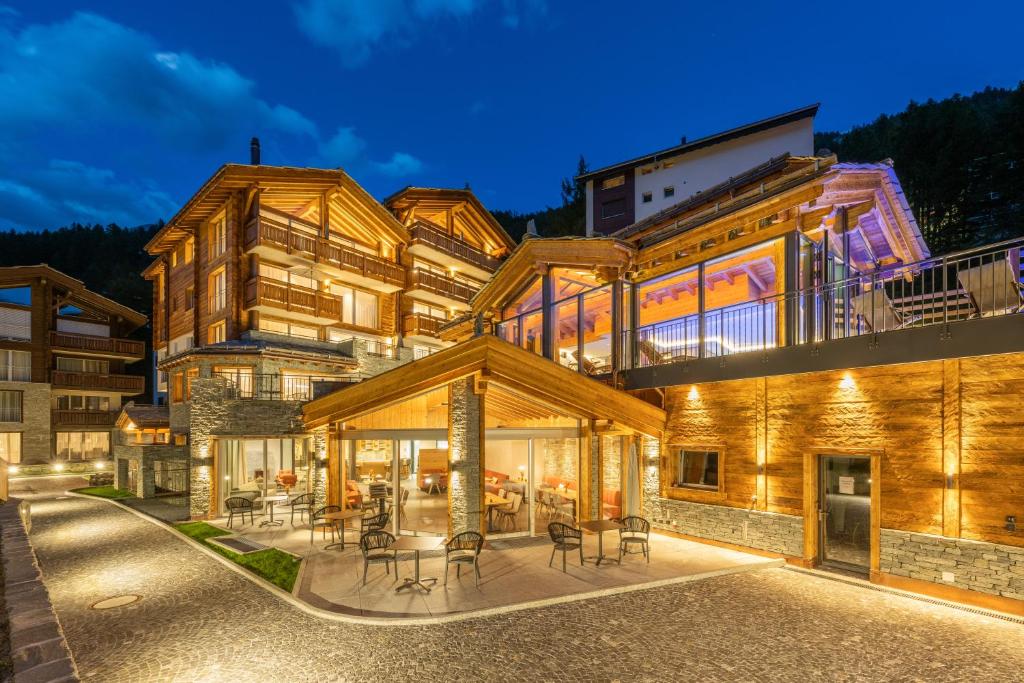 ein großes Gebäude mit Tischen und Stühlen davor in der Unterkunft Luxury Residence Colosseo Zermatt in Zermatt