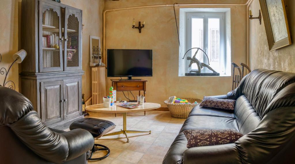 a living room with a leather couch and a television at Hotel Pascal in Allos