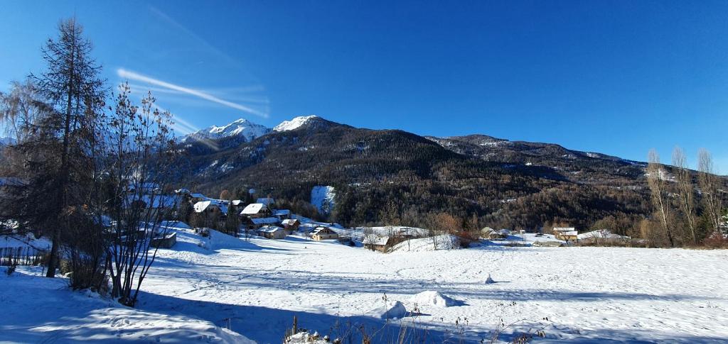 une montagne enneigée avec un village au premier plan dans l'établissement studio de charme au Melezet, les Orres. Plein Sud., aux Orres