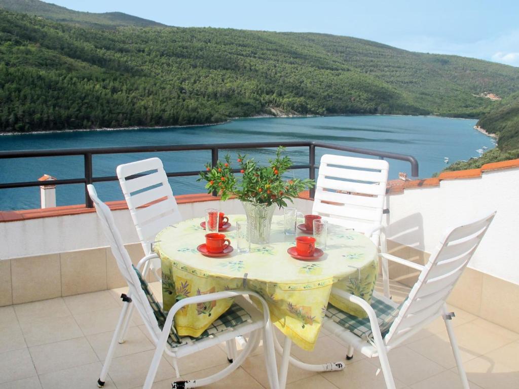 a table and chairs on a balcony with a view of the water at Apartment Violetta - LBN200 by Interhome in Labin