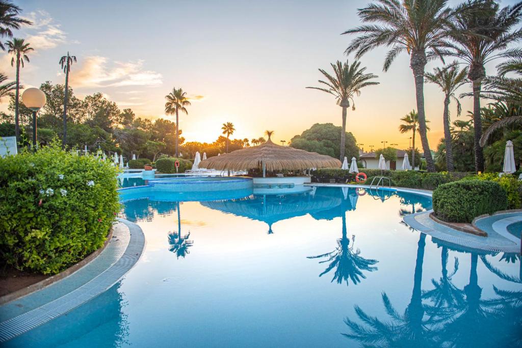 a pool at a resort with palm trees at Blau Colònia Sant Jordi in Colònia de Sant Jordi