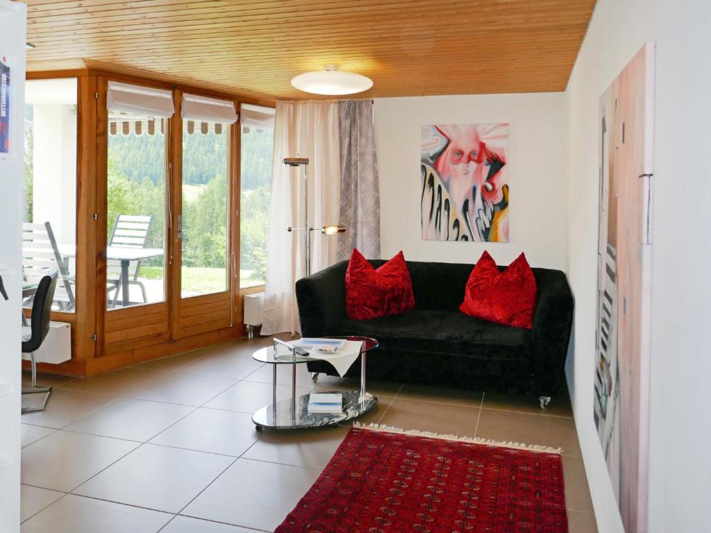 ein Wohnzimmer mit einem schwarzen Sofa und roten Kissen in der Unterkunft Apartment Chesa Piz Cotschen 2 by Interhome in Pontresina