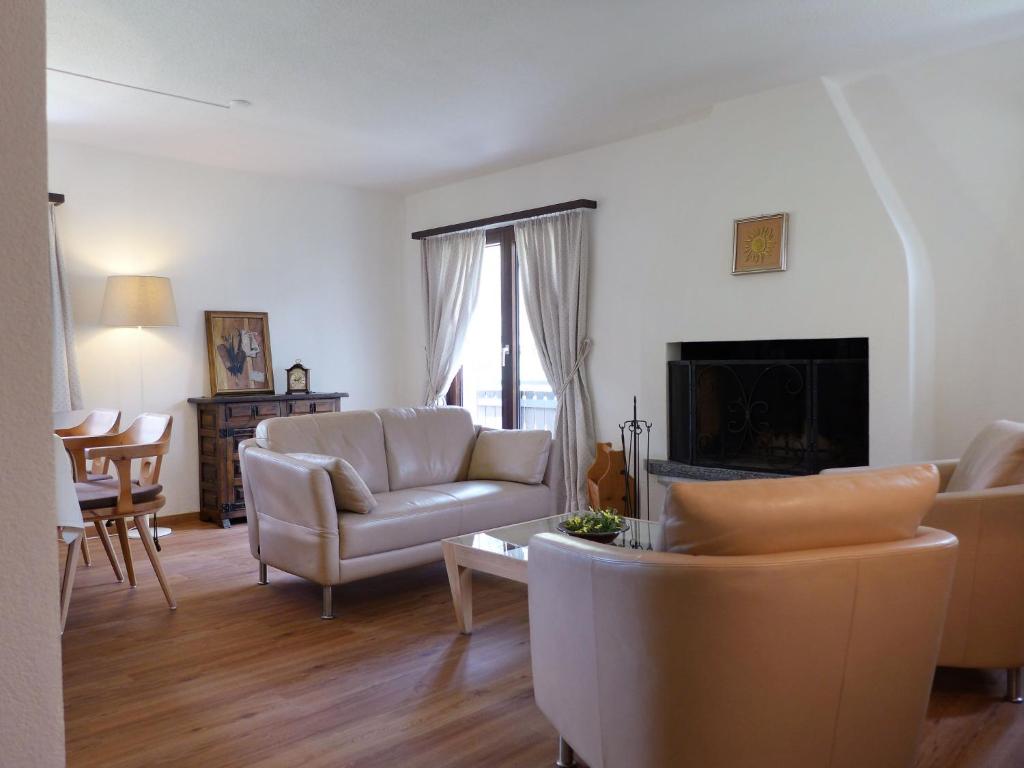 ein Wohnzimmer mit weißen Möbeln und einem Kamin in der Unterkunft Apartment Chesa Mulin by Interhome in Celerina