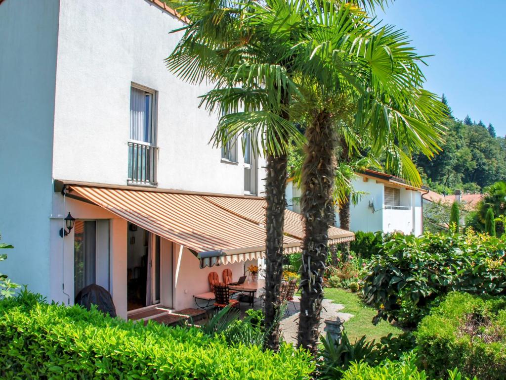 a house with a palm tree in front of it at Holiday Home Ar Ronchée N- 9 by Interhome in Astano