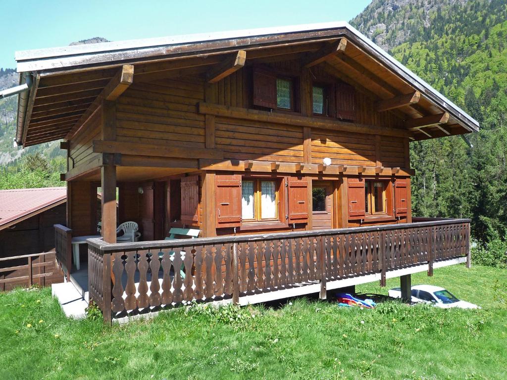 a large wooden cabin with a porch in the grass at Chalet Pierre Blanche by Interhome in Servoz