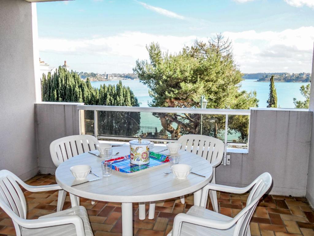 a white table and chairs with a view of the water at Apartment Terrasses d'Emeraude-1 by Interhome in Dinard