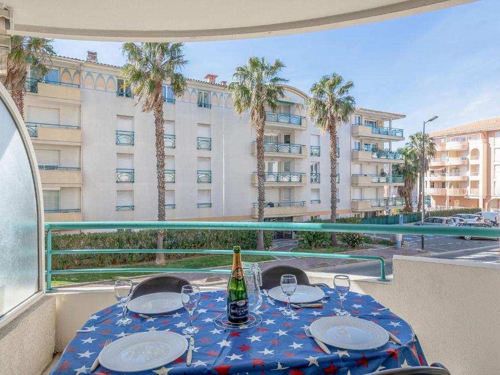 uma mesa com uma garrafa de vinho na varanda em Apartment L'Open-11 by Interhome em Fréjus