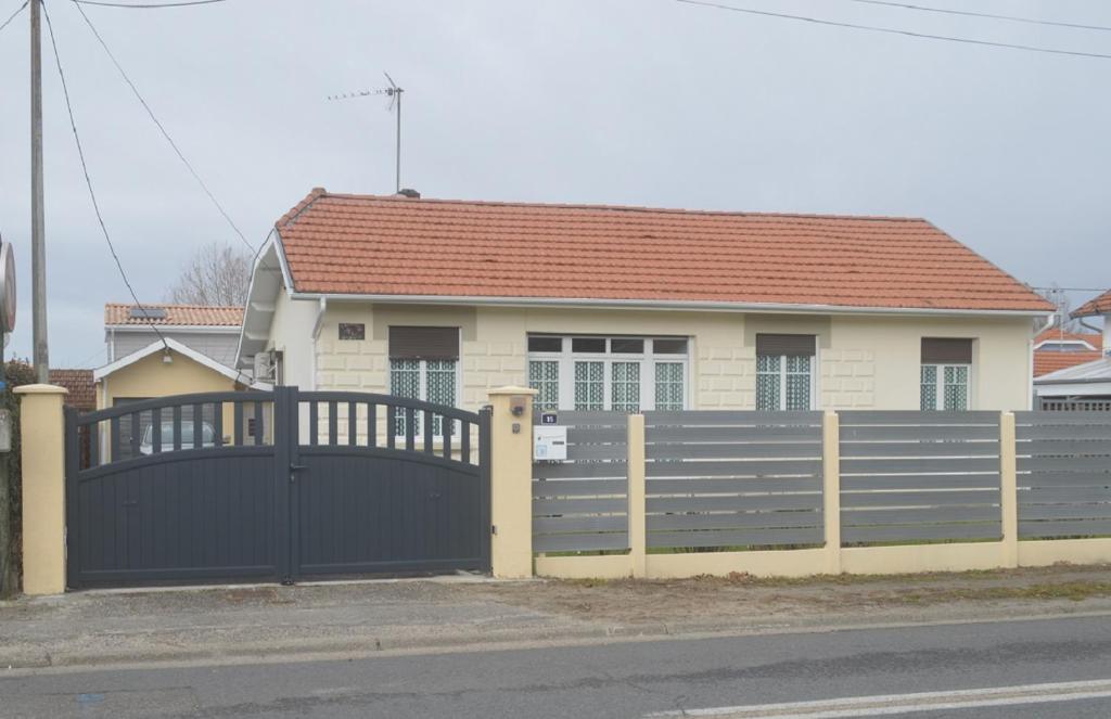 une maison avec une clôture devant elle dans l'établissement l'Orchidée, à Andernos-les-Bains